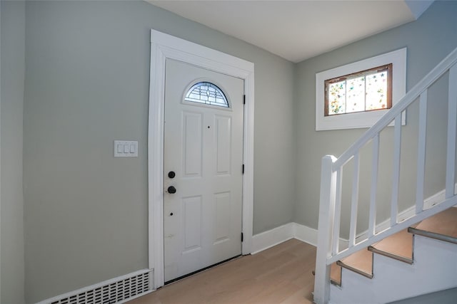 entryway featuring a healthy amount of sunlight, stairs, visible vents, and wood finished floors