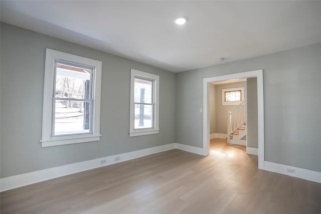 unfurnished room featuring baseboards, plenty of natural light, and light wood-style floors