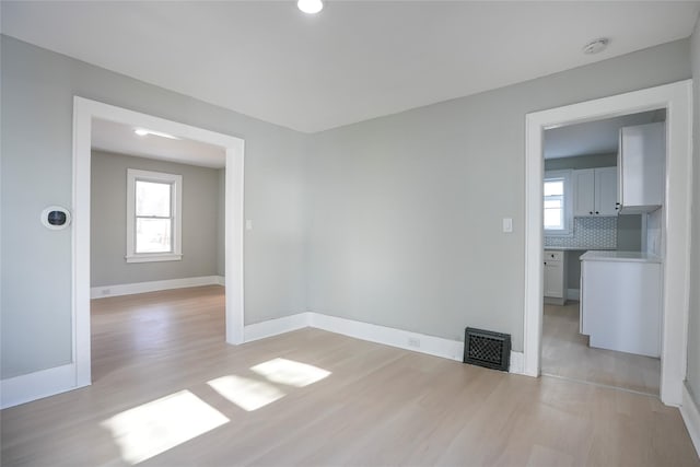 spare room with light wood-style flooring, visible vents, and baseboards