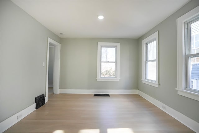 empty room featuring light wood-style flooring, visible vents, and baseboards