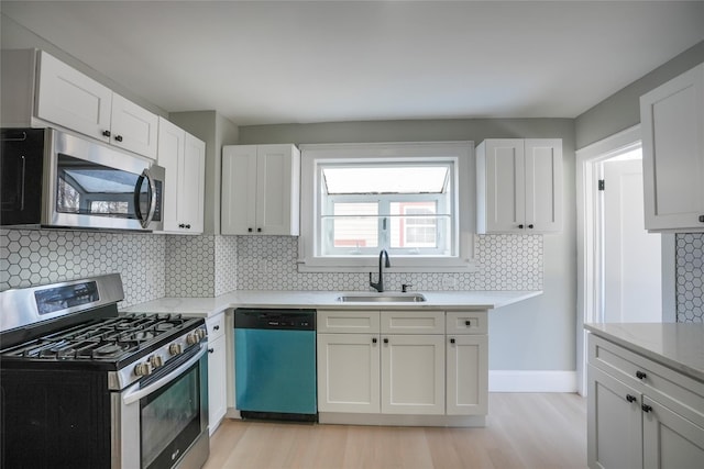 kitchen featuring stainless steel appliances, light wood-style floors, a sink, and white cabinets