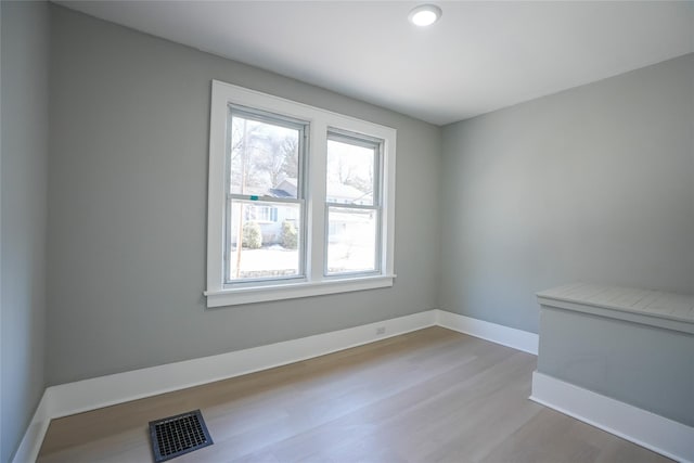 empty room featuring baseboards, visible vents, and light wood finished floors