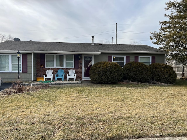 ranch-style home with brick siding, a front yard, and a shingled roof