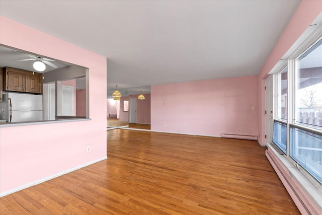 unfurnished living room with a ceiling fan, a baseboard radiator, light wood-style flooring, and baseboards