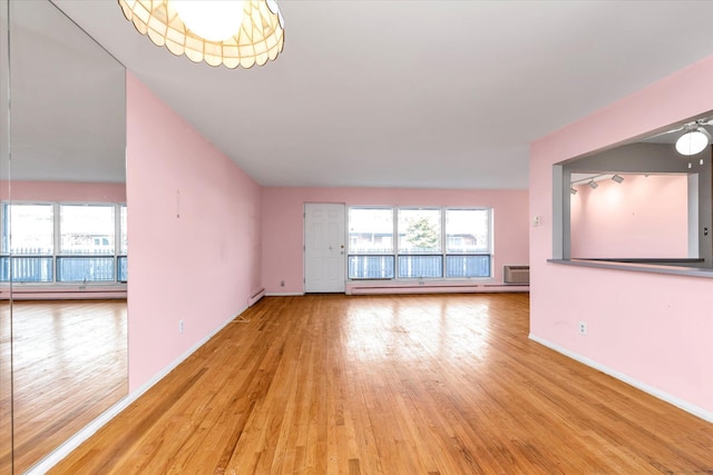 unfurnished living room with a healthy amount of sunlight, light wood-type flooring, baseboards, and a baseboard radiator