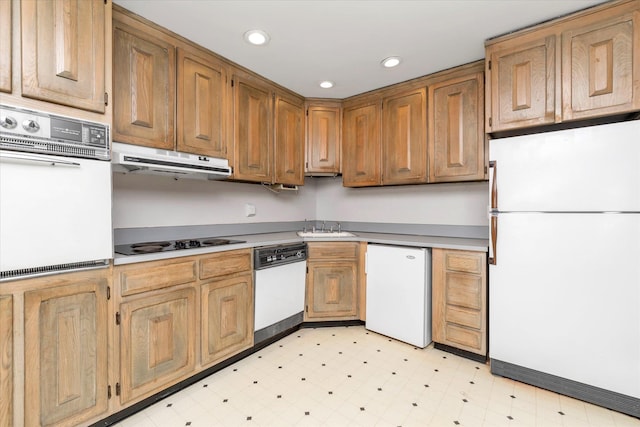 kitchen featuring white appliances, light floors, light countertops, under cabinet range hood, and a sink