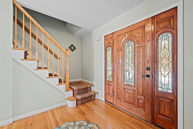 entryway with stairs, baseboards, and wood finished floors