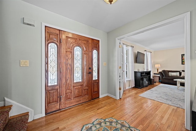 foyer entrance featuring light wood-style floors, stairway, and baseboards