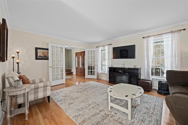 living area with a wealth of natural light, ornamental molding, wood finished floors, and french doors