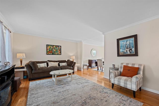 living area featuring crown molding, baseboards, and wood finished floors