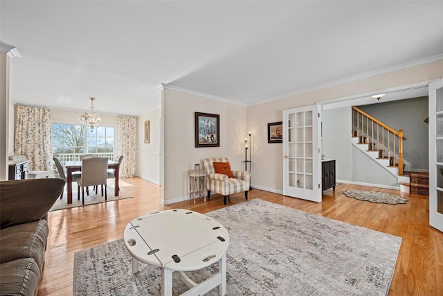 living area with crown molding, wood finished floors, a chandelier, baseboards, and stairs