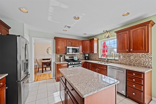 kitchen featuring a center island, visible vents, backsplash, appliances with stainless steel finishes, and a sink