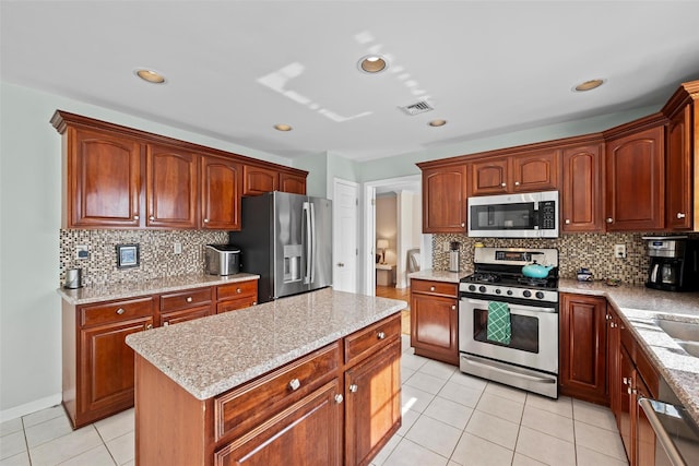 kitchen featuring light tile patterned floors, light stone counters, a kitchen island, visible vents, and appliances with stainless steel finishes