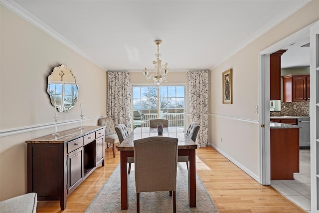 dining room with baseboards, ornamental molding, light wood-style flooring, and a notable chandelier