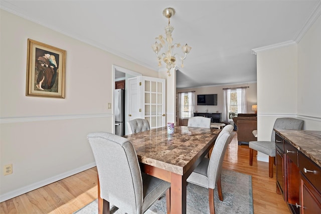 dining space with baseboards, a chandelier, light wood-style flooring, and crown molding