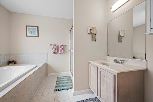 full bathroom featuring a relaxing tiled tub, vanity, baseboards, and tile patterned floors