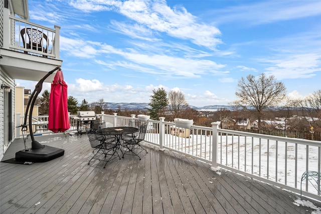 snow covered deck with outdoor dining area, grilling area, and a mountain view