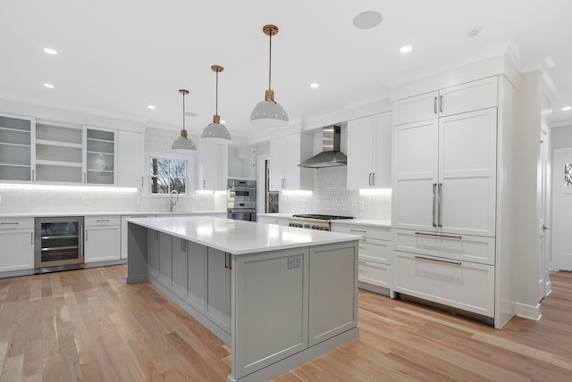 kitchen featuring wall chimney exhaust hood, wine cooler, light countertops, and light wood-style flooring