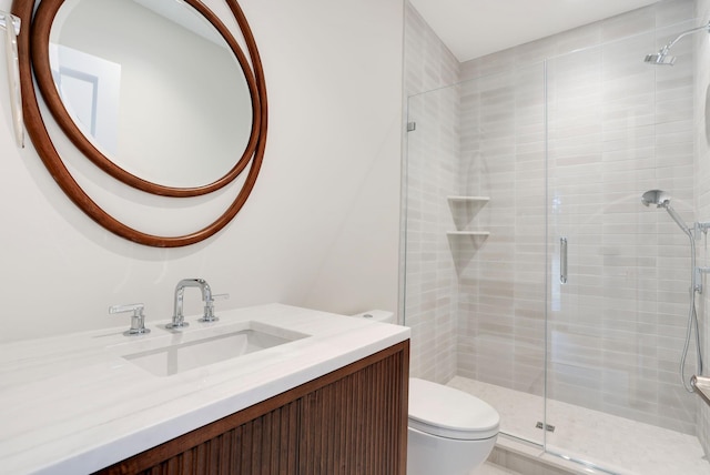 bathroom featuring toilet, a shower stall, and vanity