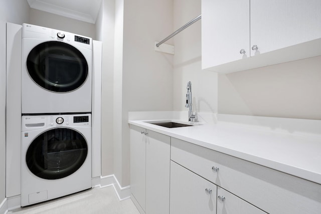 laundry room with a sink, cabinet space, ornamental molding, and stacked washer / dryer