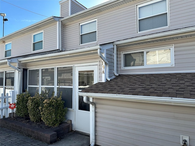 view of side of home featuring a shingled roof and a sunroom