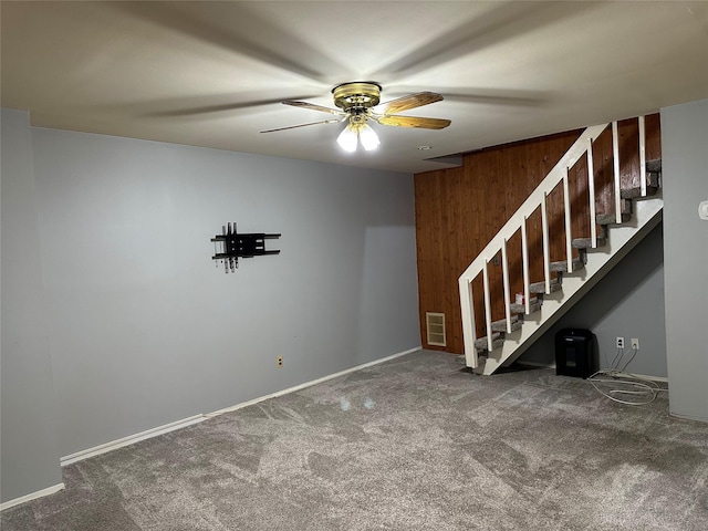 carpeted empty room featuring baseboards, stairway, visible vents, and a ceiling fan