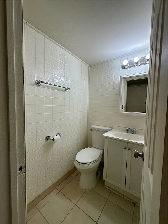 half bath with tile patterned flooring, tile walls, toilet, and vanity