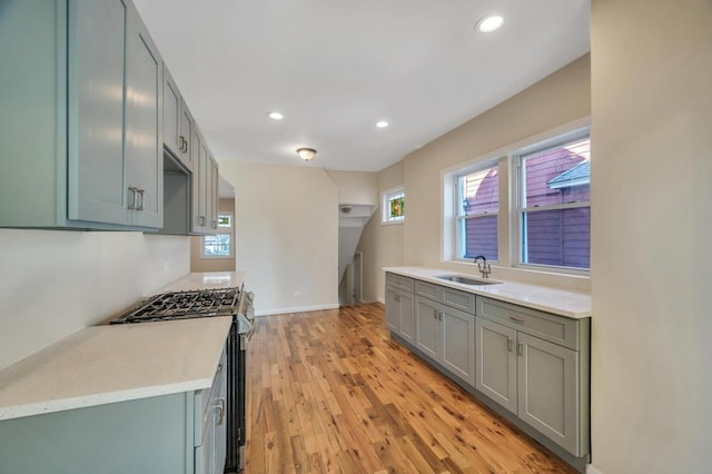 kitchen with stainless steel gas range oven, sink, and light wood-type flooring