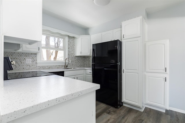 kitchen featuring sink, stove, black fridge, dark wood-type flooring, and white cabinets