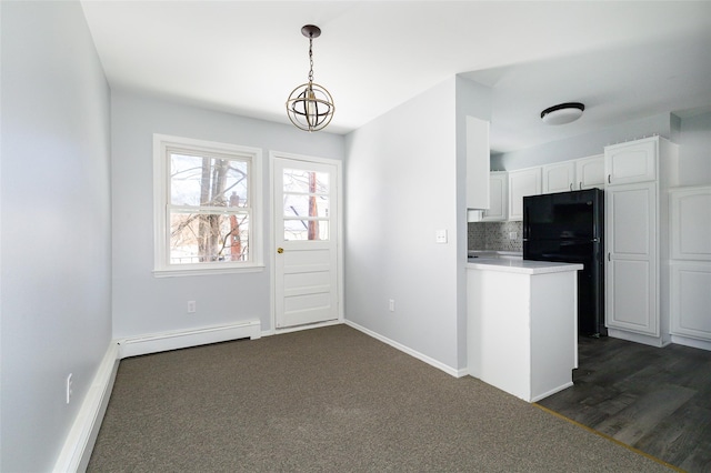 kitchen with tasteful backsplash, hanging light fixtures, black refrigerator, white cabinets, and baseboard heating