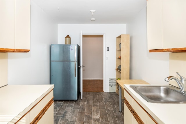 kitchen featuring white cabinetry, light countertops, a sink, and freestanding refrigerator