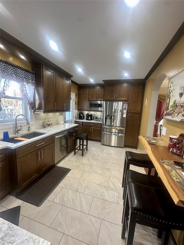 110-37 213th St, Queens Village, NY 11429 - kitchen featuring stainless steel appliances, dark brown cabinetry, sink, crown molding, and decorative backsplash
