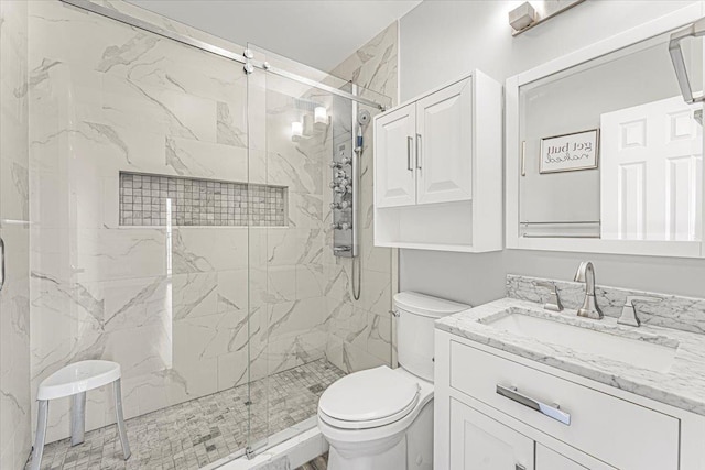 full bath featuring toilet, a marble finish shower, and vanity