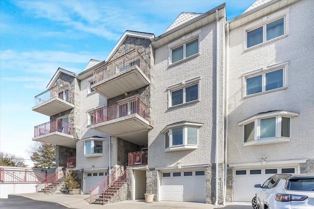 view of building exterior with a garage, driveway, and stairway