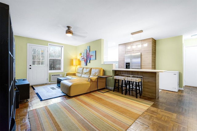 living room featuring ceiling fan, a wall unit AC, and dark parquet flooring