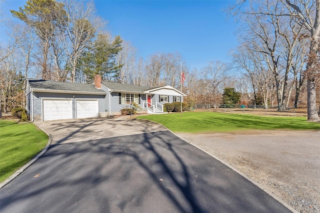 view of front of property with a garage, fence, driveway, a front lawn, and a chimney