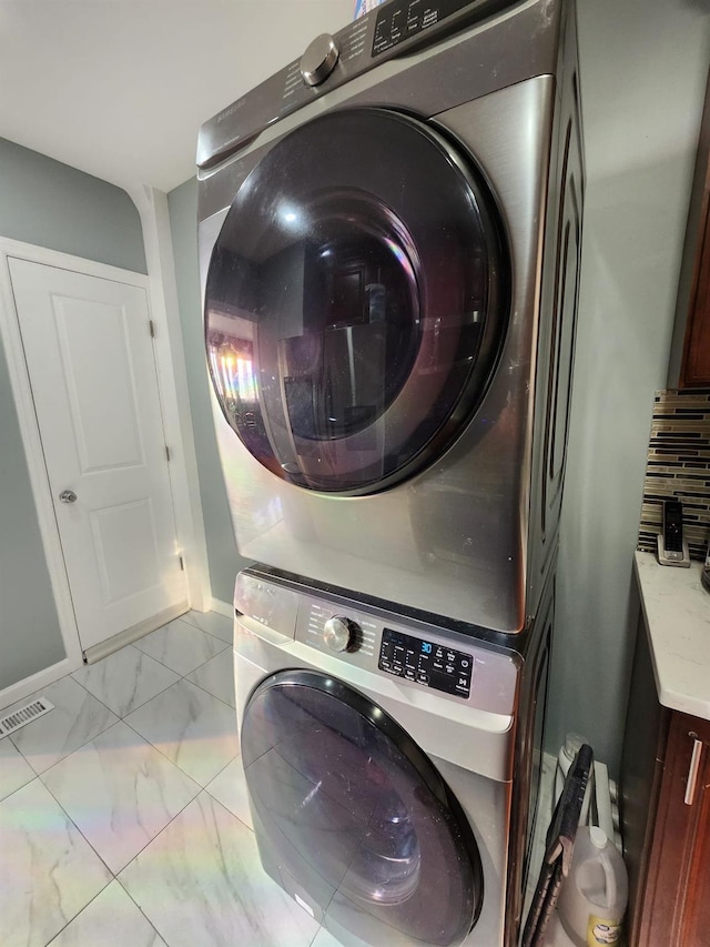 laundry room featuring cabinets and stacked washer and clothes dryer