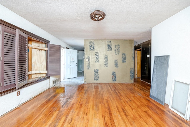 empty room featuring light wood-type flooring and a textured ceiling