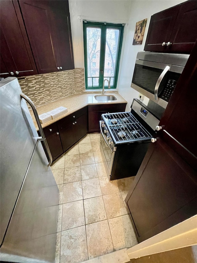 kitchen featuring dark brown cabinetry, sink, light tile patterned floors, appliances with stainless steel finishes, and decorative backsplash