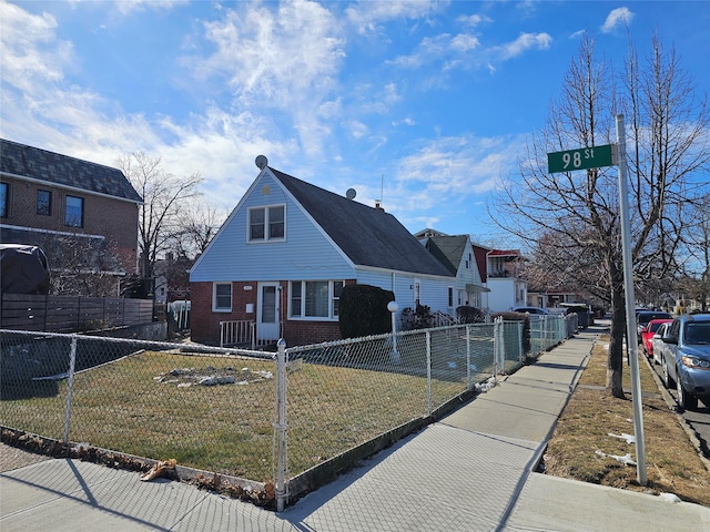 view of front of home with fence private yard, brick siding, a residential view, and a front lawn