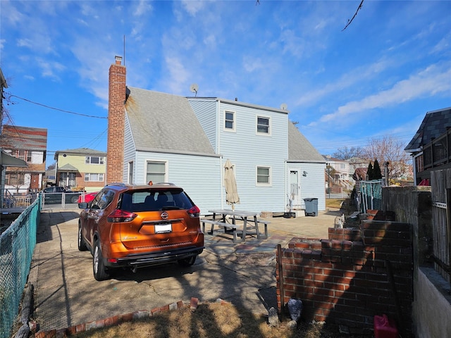 back of property featuring a shingled roof, entry steps, fence, and a chimney