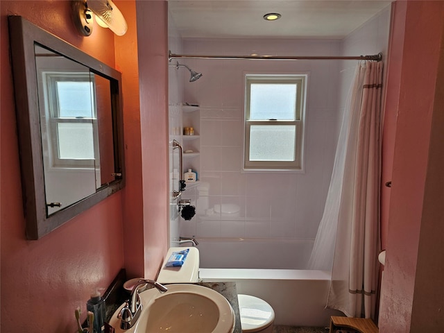 bathroom featuring toilet, shower / bathtub combination with curtain, and a sink