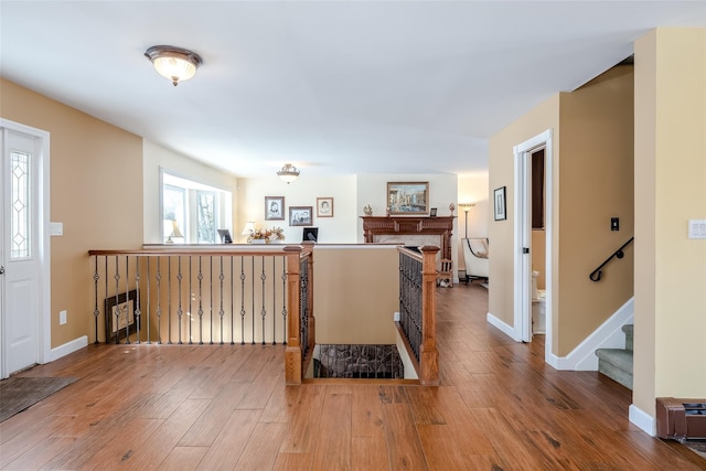 foyer entrance with a fireplace, baseboards, and wood finished floors