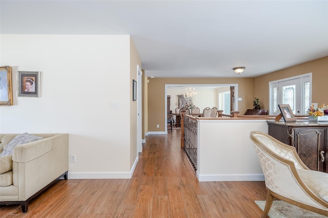 interior space featuring light wood-style floors, baseboards, and a chandelier