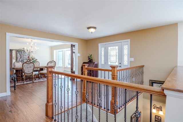 hall featuring a chandelier, wood finished floors, and an upstairs landing