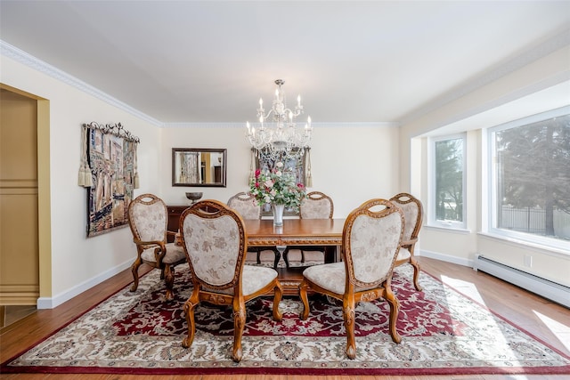 dining space with a chandelier, crown molding, baseboards, and wood finished floors