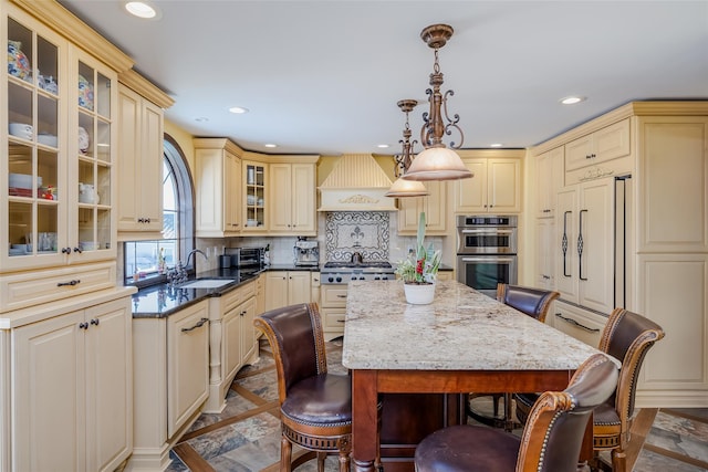 kitchen featuring a breakfast bar area, stainless steel appliances, a kitchen island, a sink, and custom range hood