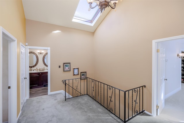 stairs with carpet floors, a skylight, high vaulted ceiling, and baseboards