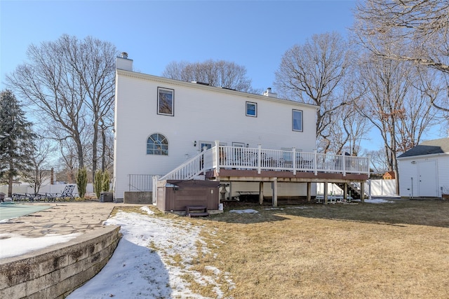 rear view of house featuring an outbuilding, a chimney, a storage unit, a hot tub, and a wooden deck