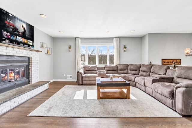 living room featuring dark wood-style floors, a fireplace, visible vents, and recessed lighting